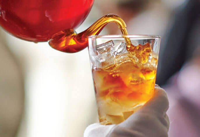 Tea being Poured into a glass filled with Ice